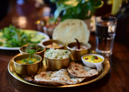 A closeup shot of an Indian tasty food called "Marwari Veg Thali" on the wooden table